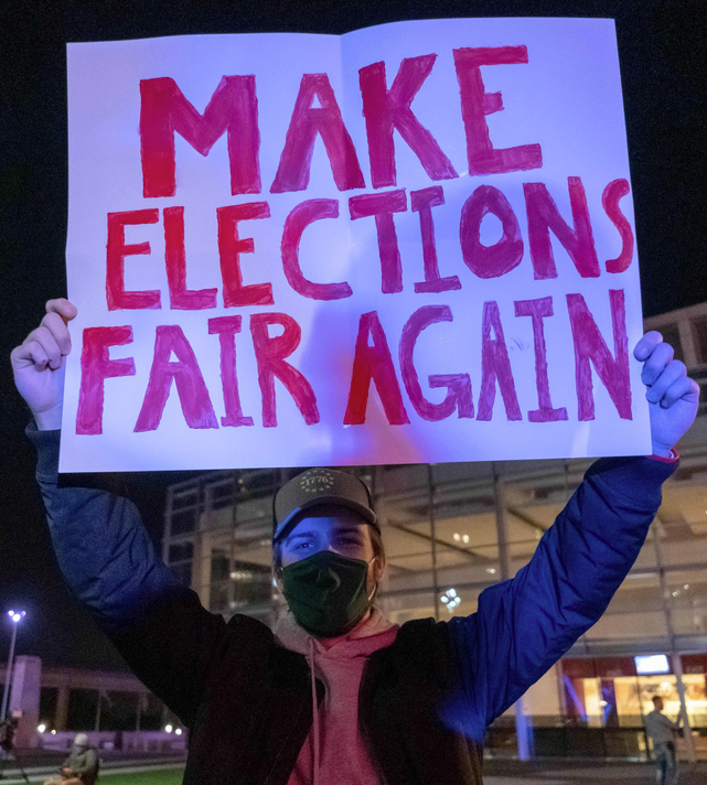 	A supporter of US President Donald Trump holds a sign during a protest outside of the TCF Center where ballots are being counted, in Detroit, Michigan on November 5, 2020. - President Donald Trump erupted on November 5 in a tirade of unsubstantiated claims that he has been cheated out of winning the US election as vote counting across battleground states showed Democrat Joe Biden steadily closing in on victory
