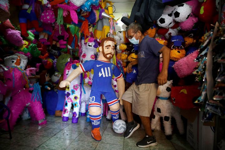 Nelson Sánchez poses with his latest creation in San Salvador en El Salvador, a piñata of Messi in the PSG shirt.