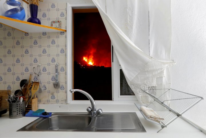 Lava is seen through the window of a kitchen in El Paso following the eruption of a volcano on the Canary Island of La Palma, Spain, September 28, 2021. REUTERS/Jon Nazca/File Photo