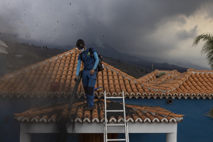 Cleaner on the roof of a ash-covered house