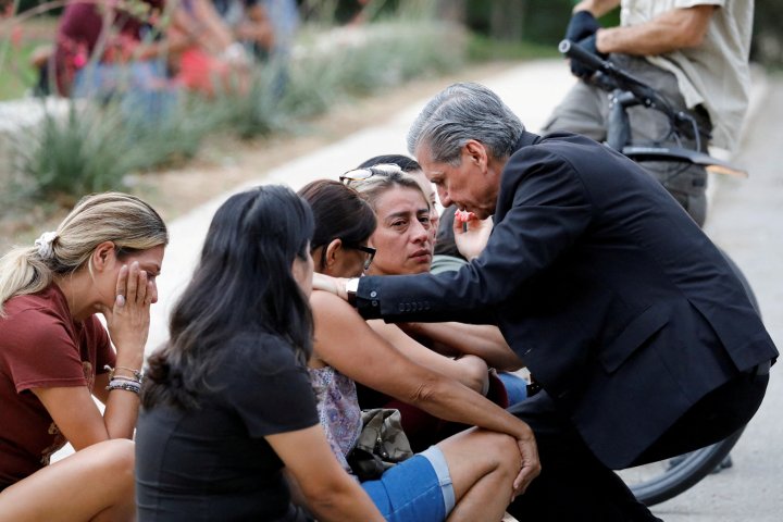 Gustavo Garcia-Siller, Archbishop of the Archdiocese of San Antonio, comforts people as they react outside the Ssgt Willie de Leon Civic Center, where students had been transported from Robb Elementary School after a shooting, in Uvalde, Texas, U.S. May 24, 2022.  REUTERS/Marco Bello