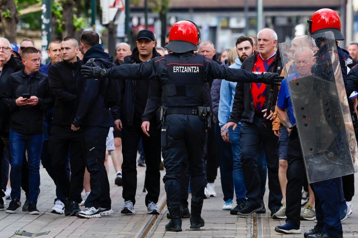 Un agente de la Ertzaintza corta el paso a los aficionados visitantes cerca de San Mamés