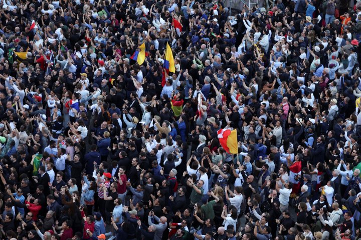 Faithful react to white smoke from the chimney on the Sistine Chapel indicating that a new pope has been elected, at the Vatican, May 8, 2025. REUTERS/Claudia Greco